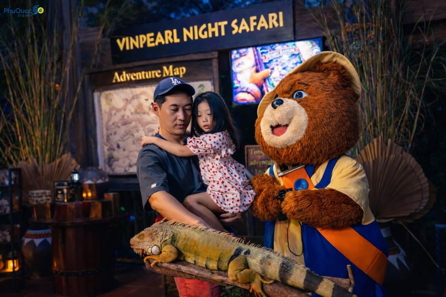 Hai bố con chụp ảnh kỷ niệm cùng mascot gấu và một chú cự đà lớn iguana tại khu vực Night Safari Phú Quốc ban đêm