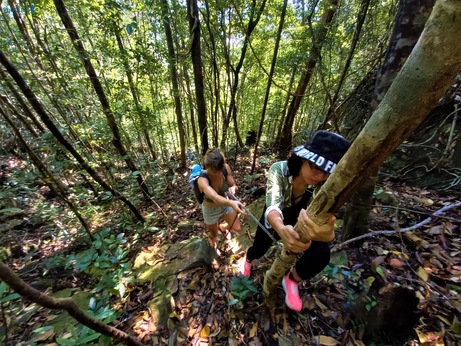 Hiker holding ropes to overcome a steep incline climbing Da Bac Mountain Phu Quoc