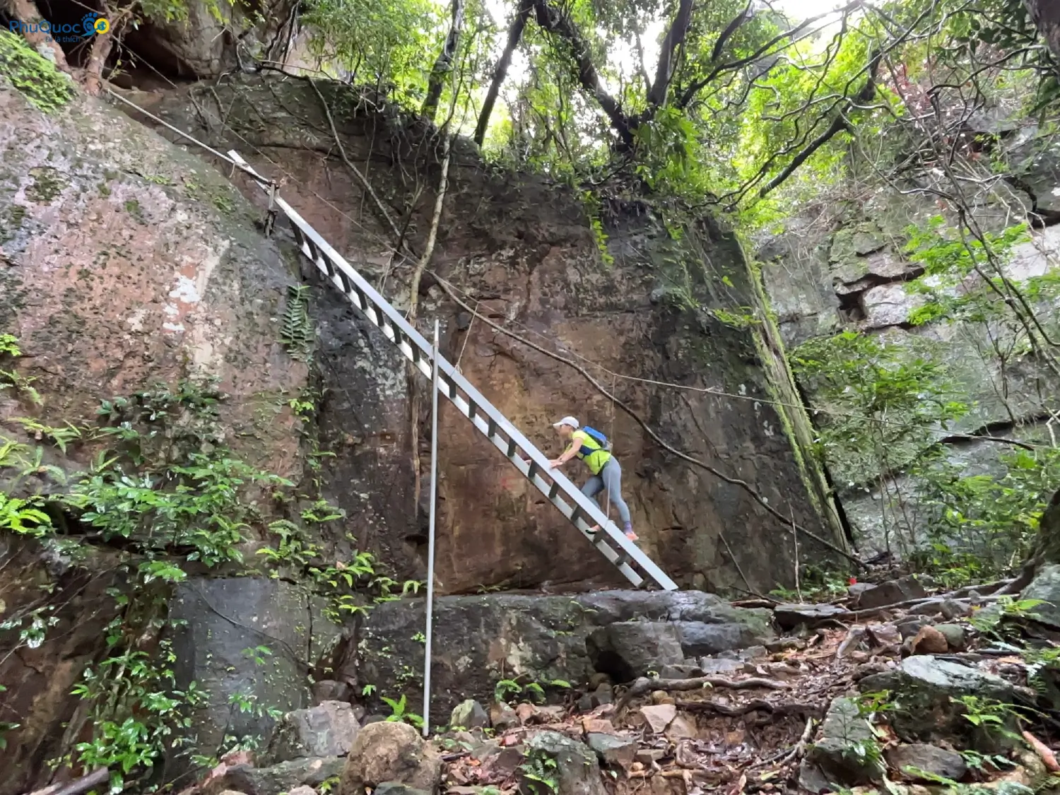 Tourists climbing iron ladders and holding ropes to scale steep rock faces on Tien Son Peak