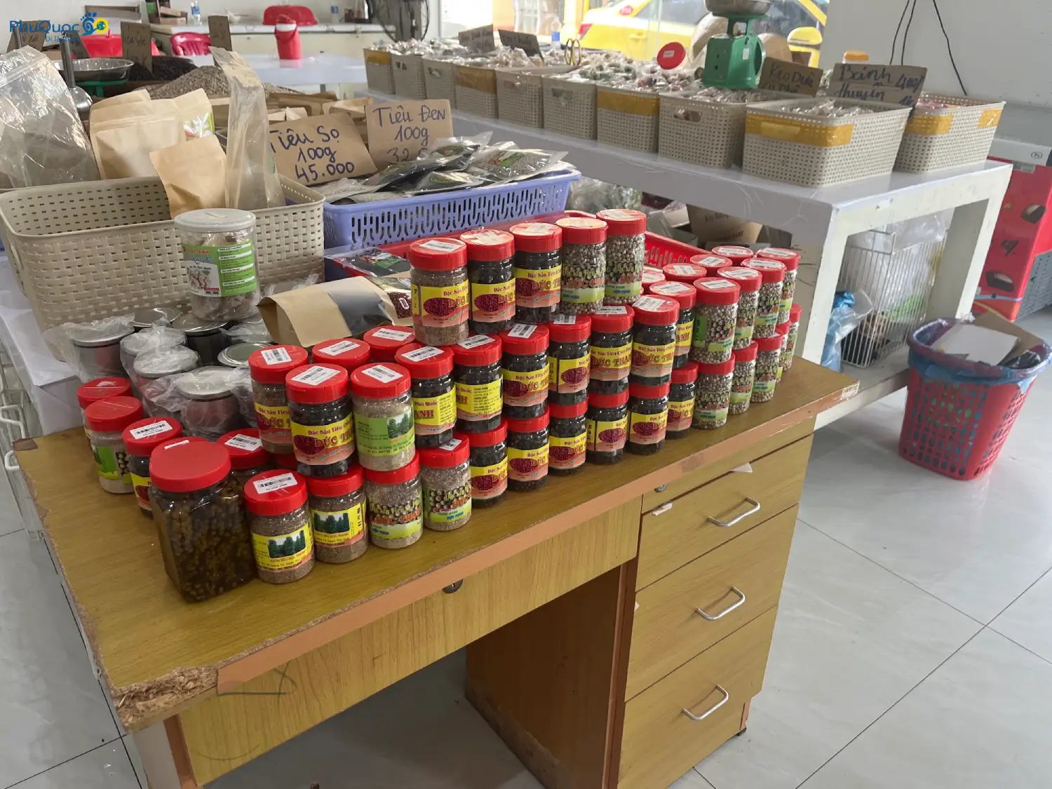 Các hũ tiêu Phú Quốc thương hiệu Đức Thạnh (tiêu sọ, tiêu đen) và các sản phẩm đặc sản được bày bán trên bàn gỗ với biển giá viết tay mộc mạc.