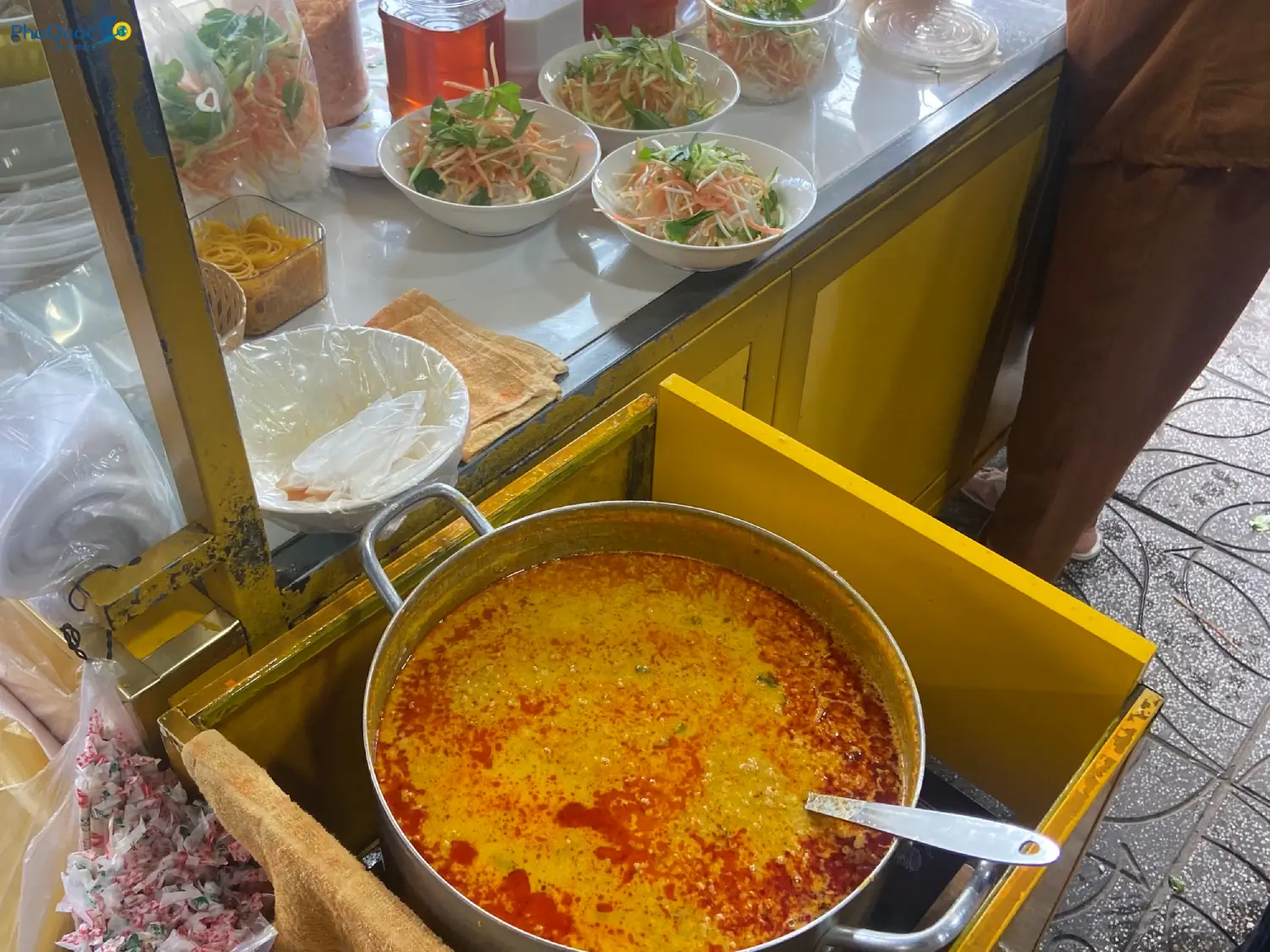 A pot of rich amber yellow bun ken broth being prepared at the original Ut Luom Bun Ken stall